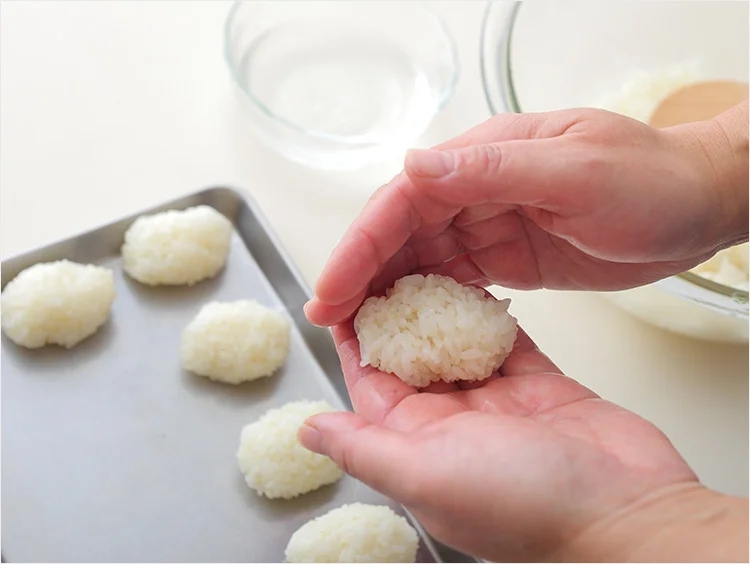 Đôi tay đang nặn viên bánh nếp trắng bên cạnh các viên bánh nhỏ