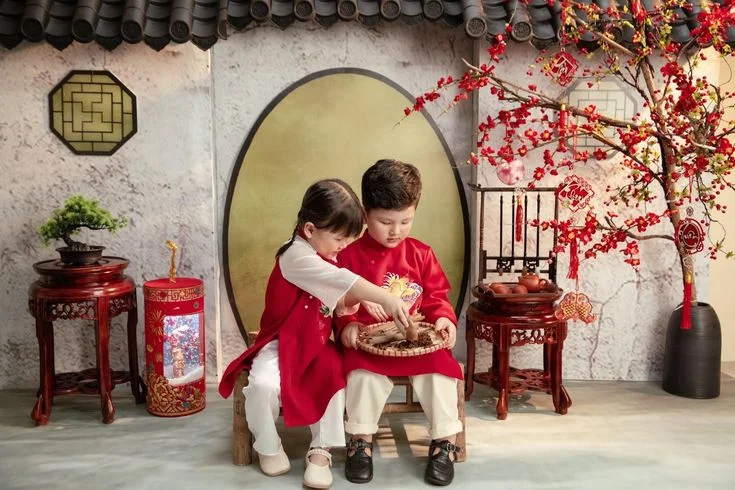 Gia đình mặc trang phục đỏ chụp ảnh bên hoa đào và không gian trang trí Tết