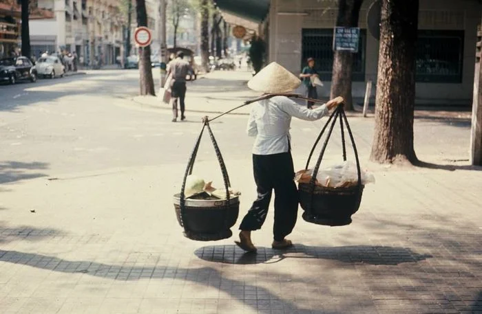 Người phụ nữ đội nón lá gánh hàng trên phố